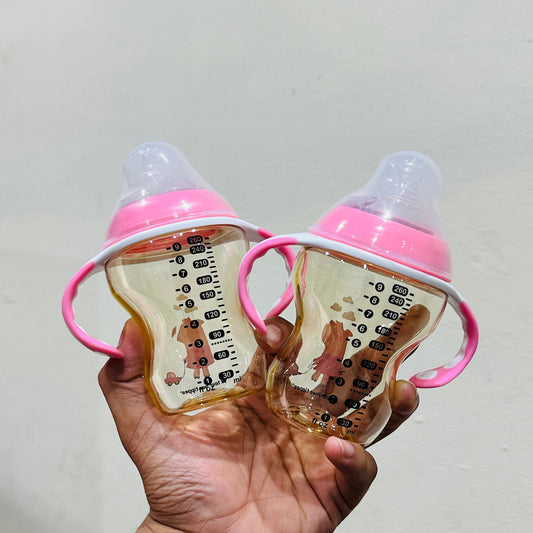 Two Tommee baby bottles with pink handles