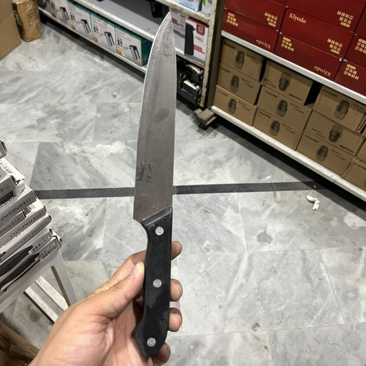 Person holding a knife in a store setting with shelves and products in the background